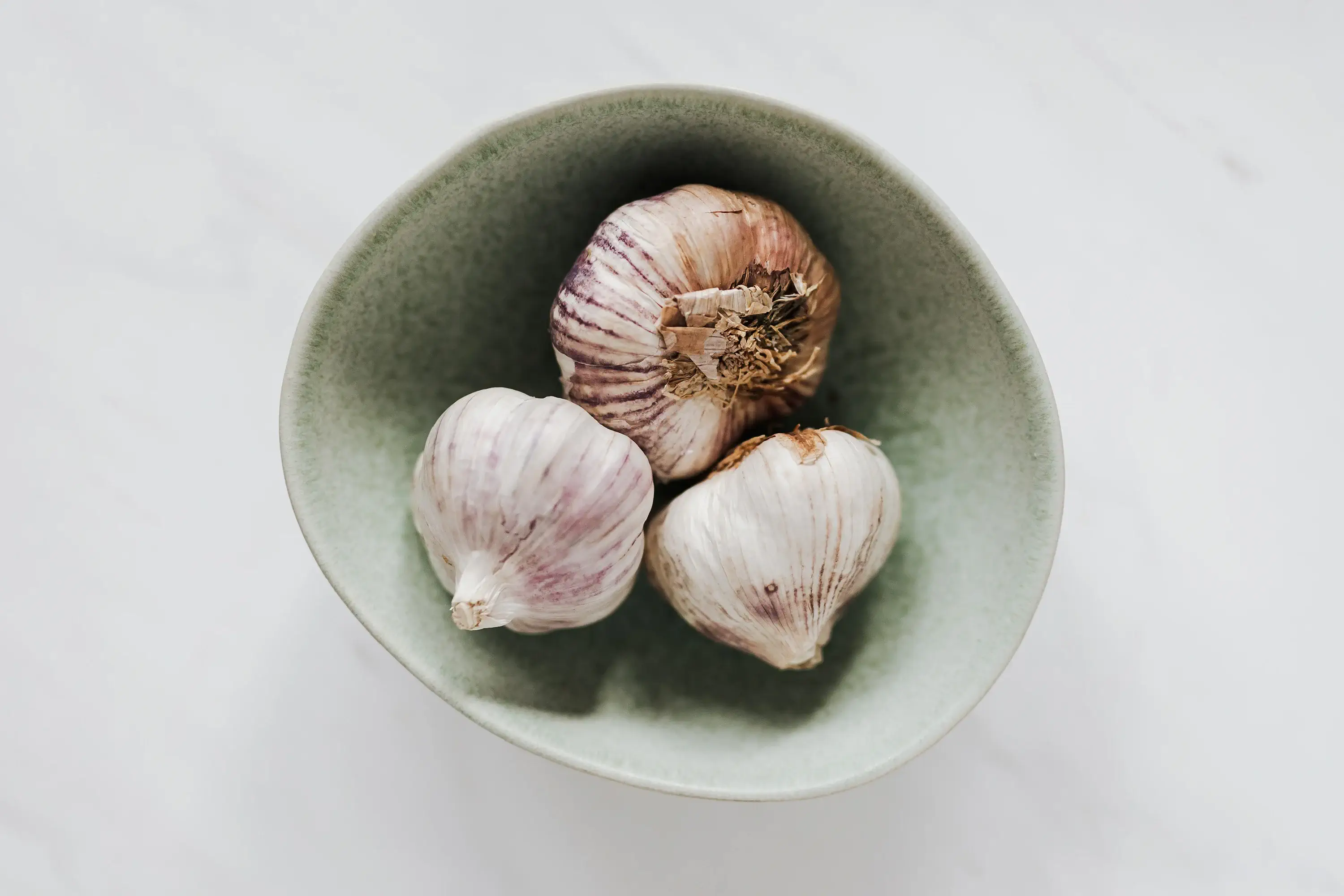 three onions in a small green bowl